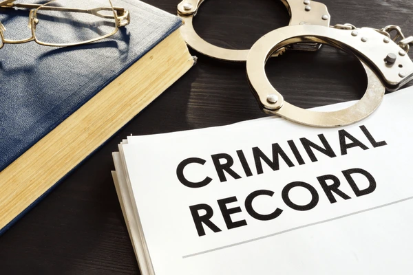 criminal-record-handcuffs-on-desk-600nw-1174972870